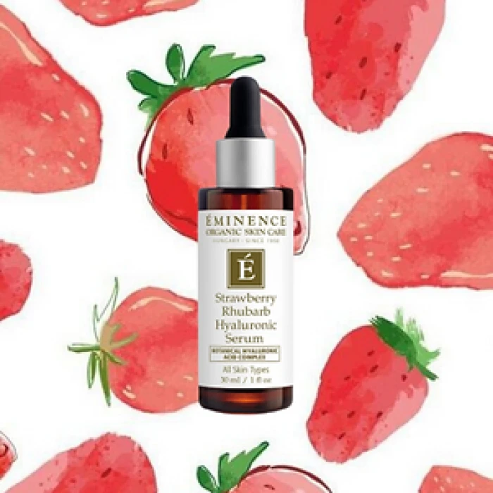 A bottle of Eminence Strawberry Rhubarb Hyaluronic Serum, surrounded by illustrated strawberries on a white background.